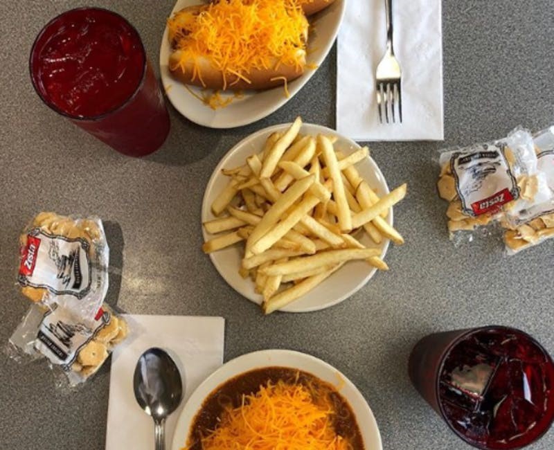 a table of fries, a three way, a chili cheese coney, bags of crackers and water from camp washington chili