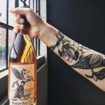 tattooed arm holding Skeleton Root wine bottle is one of the popular cincinnati drinks