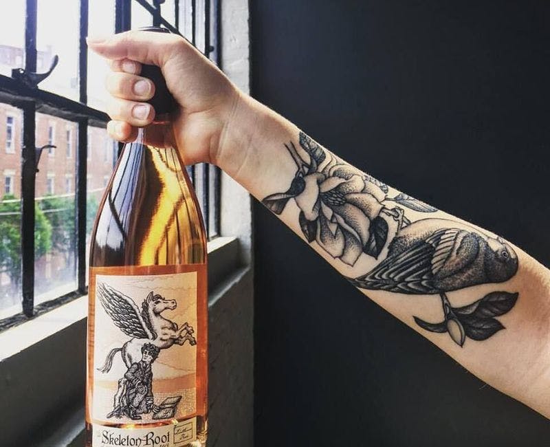 tattooed arm holding Skeleton Root wine bottle is one of the popular cincinnati drinks