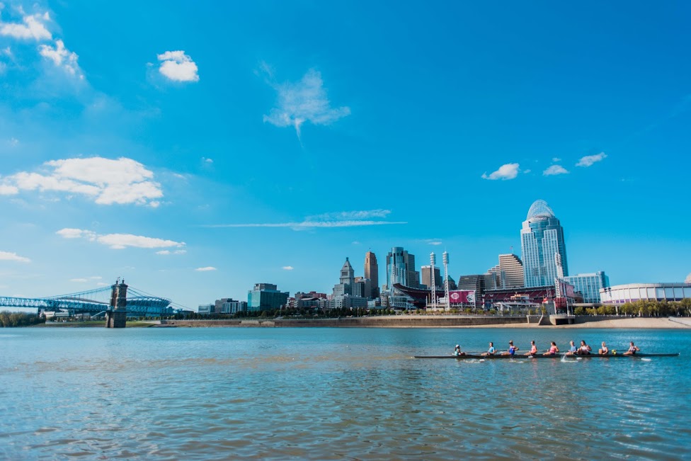 people rowing on the ohio river with cincinnati skyline in the background